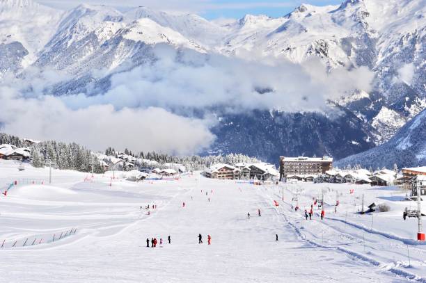 Ski resort with skiing people on wide ski slope Ski village with skiing people courchevel stock pictures, royalty-free photos & images