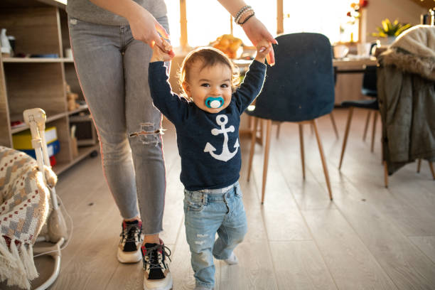 Happy baby boy learning to walk Unrecognizable female person holding hands of a happy smiling Little boy ,learning to walk nanny photos stock pictures, royalty-free photos & images