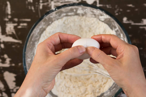 istock Woman hand crack egg into flour to make dough on brown background 1212172732