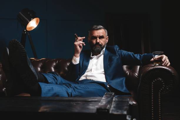 istock Attractive man with cigar and a glass whiskey 1212176401