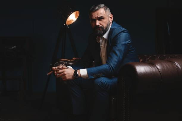 istock Attractive man with cigar and a glass whiskey 1212176415