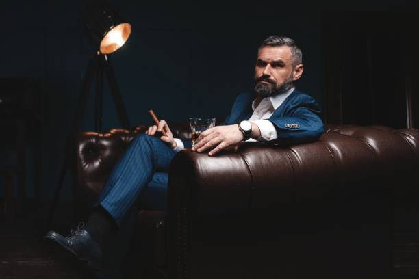 istock Attractive man with cigar and a glass whiskey 1212176416