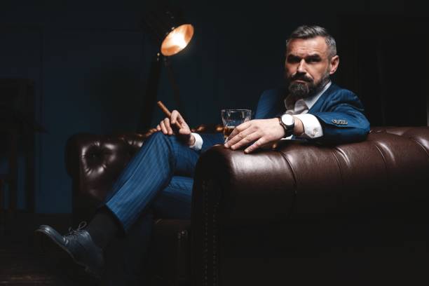 istock Attractive man with cigar and a glass whiskey 1212176417