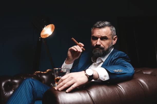 istock Attractive man with cigar and a glass whiskey 1212176418