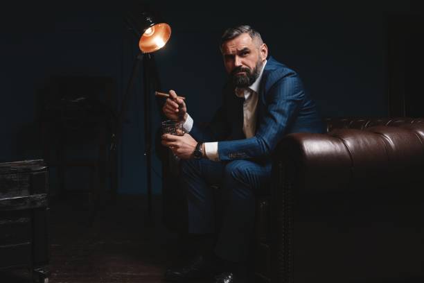 istock Attractive man with cigar and a glass whiskey 1212176425