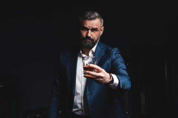 istock Attractive man with cigar and a glass whiskey 1212176432