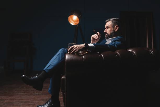 istock Attractive man with cigar and a glass whiskey 1212176461