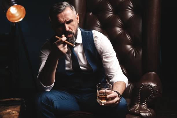 istock Attractive man with cigar and a glass whiskey 1212176835