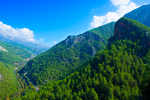 Top view of high mountains covered by forest, blue sky with white clouds on a sunny summer day. Toros Mountains, Turkey.