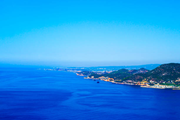 istock Blue sea, clear cloudless sky and shore with green hills, top view. 1212177437
