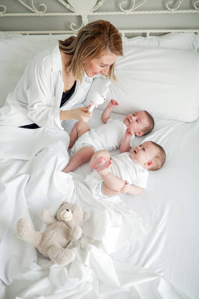 istock Mother With Twin Babies Playing Happily in Her Bedroom 1212178968