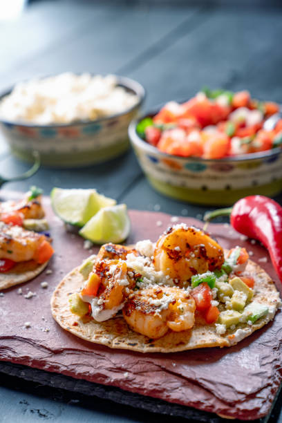 Colorful Street Tacos, Shrimp - Seafood, Fish, Grilled, Ready-To-Eat A beautiful arrangement of shrimp tacos with pico de gallo, avocado, cilantro, chipotle sour cream, and cotija cheese cajun food photos stock pictures, royalty-free photos & images