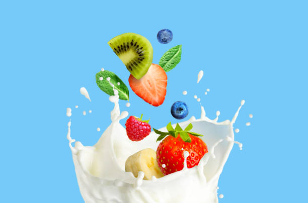 fruit berry mix falling in milk and splashing isolated on blue background. smoothie or milkshake prepearing. - falling fruit berry fruit raspberry imagens e fotografias de stock