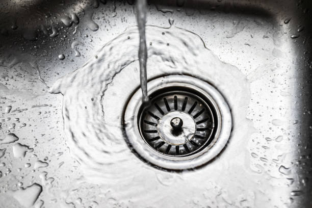 istock Water flowing down the hole into the stainless steel sink 1212190618