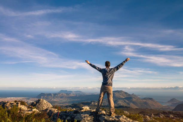 man standing with raised hands on top of table mountain in cape town, south africa - sky sea town looking at view imagens e fotografias de stock