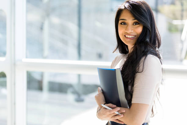 istock Young adult female student carrying notebook on way to class 1212201383