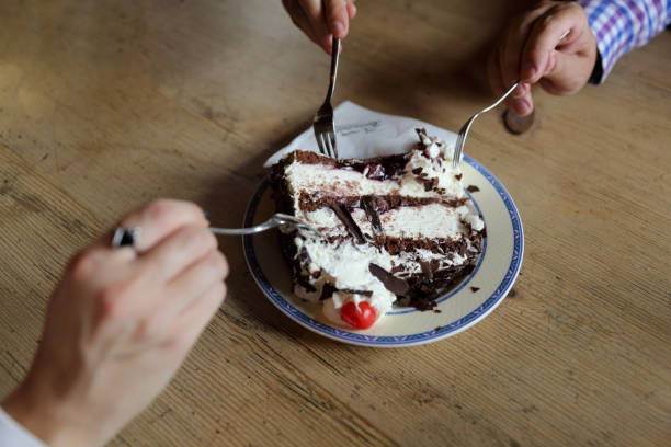People sharing black forest cake in a cafe