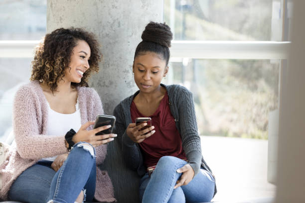 istock Smiling college friends use smartphones 1212211587