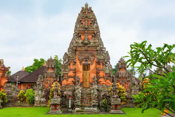 Details of traditional balinese hindu temple. Entrance gate with door, stone carving, Bhoma sprit face, guards sculptures. Popular travel destinations, art, culture festivals of Bali island, Indonesia