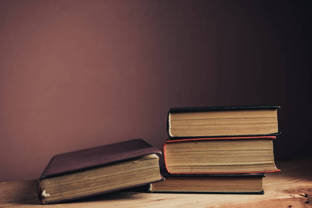 istock Vintage ancient books. Pattern background for design. The book on a brown wooden table table and red wall background. 1212214594