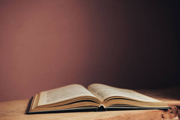 istock Beautiful open vintage ancient book. Pattern background for design. The book on a red wooden table and red wall background. 1212215534