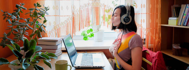 Female in headphones sits at front of laptop and breathing. Online audio meditation concept. Female in headphones sits at front of laptop and breathing. Online audio meditation concept mantra stock pictures, royalty-free photos & images