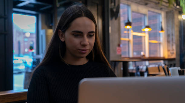 istock Young charming female freelancer using laptop computer for distance job while sitting in modern coffee shop interior, beautiful Caucasian woman working on net-book 1212218021