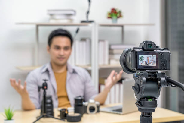 Closeup Camera taking video and live with laptop of Asian Vlogger man Camera taking video and live with laptop of Asian Vlogger man satisfied the camera lens each media, sharing knowledge to audience via camera how to sell my photography online stock pictures, royalty-free photos & images