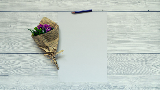 Flat lay of blank paper and flower mockup copy space on white wood background