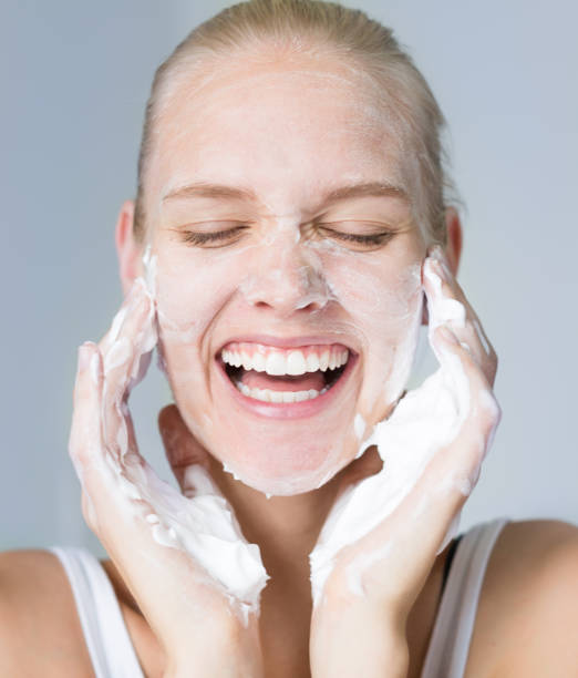 pretty woman cleansing her face with water and soap. beauty and skincare. - facial cleanser imagens e fotografias de stock