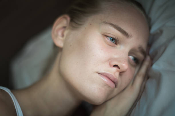 A unhappy miserable person lying on her pillow suffering from deep depression.