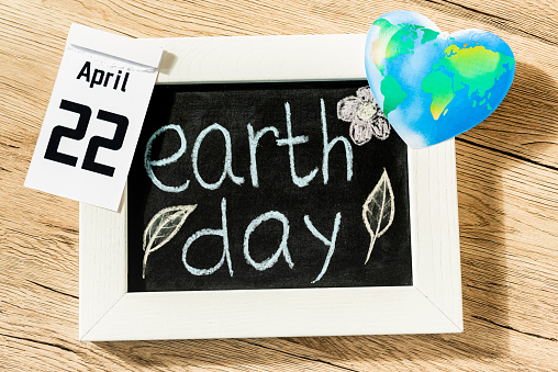 Top view of board with earth day lettering, globe and calendar with 22 april inscription on wooden background