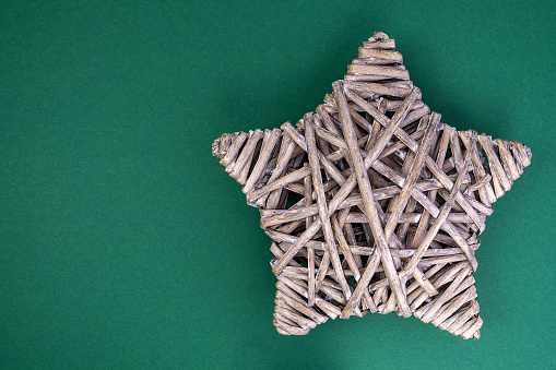 star made of rattan isolated on green background made of photo cardboard