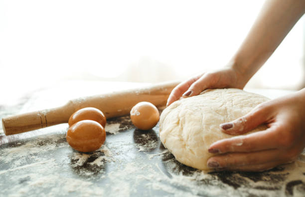 istock Making dough by female hands on wooden table background. Cooking concept. 1212229512