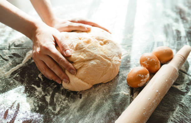 istock Making dough by female hands on wooden table background. Cooking concept. 1212229656