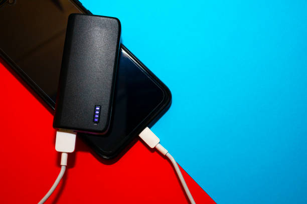 istock Powerbank loading a cell phone on a blue and red background. 1212229684