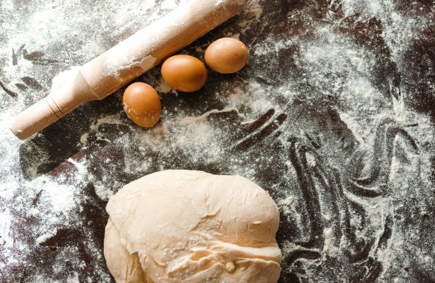 istock Dough, rolling pin, egg and flour on wooden table. Raw pizza dough with ingredients on the kitchen table. 1212229695