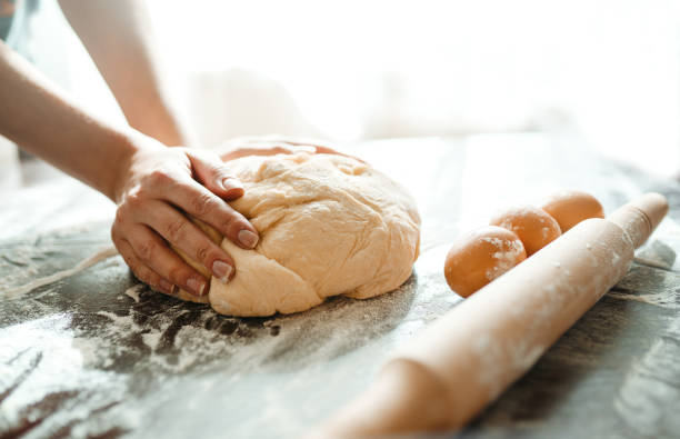 istock Making dough by female hands on wooden table background. Cooking concept. 1212229698