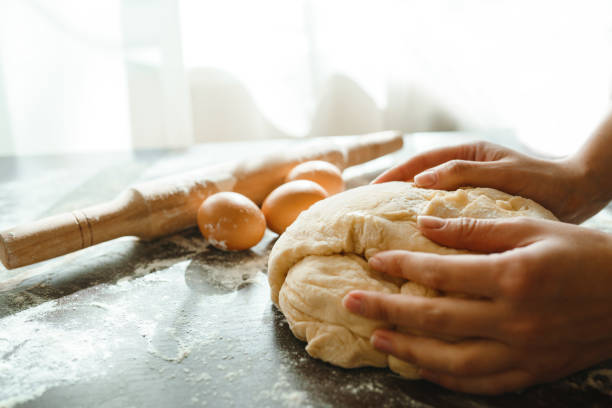 istock Making dough by female hands on wooden table background. Cooking concept. 1212229710
