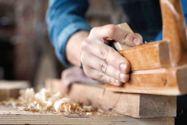 istock carpenter working with plane on wooden background. 1212230486