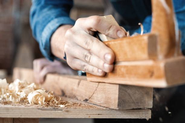 istock carpenter working with plane on wooden background. 1212230497