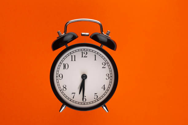 czarny budzik na pomarańczowym tle. wolne miejsce na napis. - clock time alarm clock orange zdjęcia i obrazy z banku zdjęć