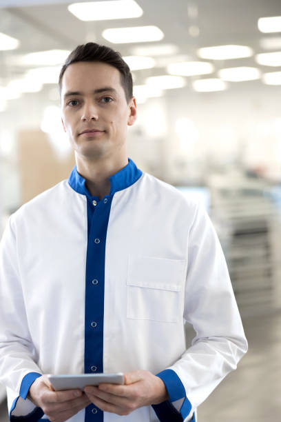 istock Handsome young man in lab coat holding digital tablet 1212235314