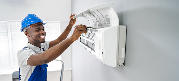 Happy Young African Male Technician Repairing Air Conditioner