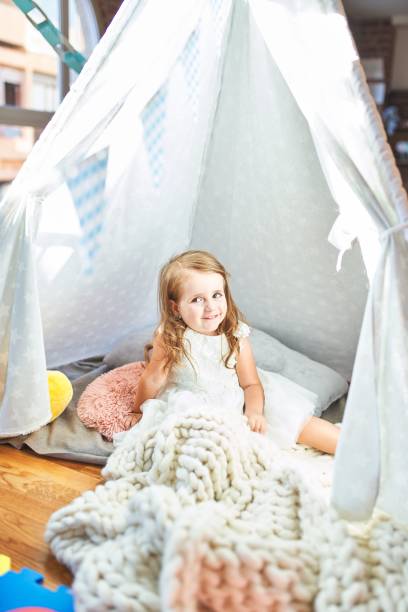 istock Adorable blonde toddler playing sitting on blanket inside tipi at kindergarten 1212236874