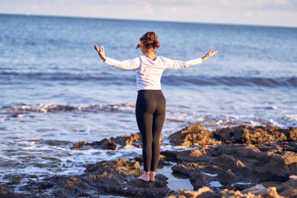 istock Young beautiful sportwoman practicing yoga. Coach teaching postures at the beach 1212237096
