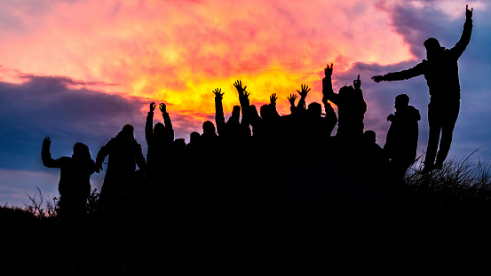 Silhouette, group of happy people jumping in sunset - image