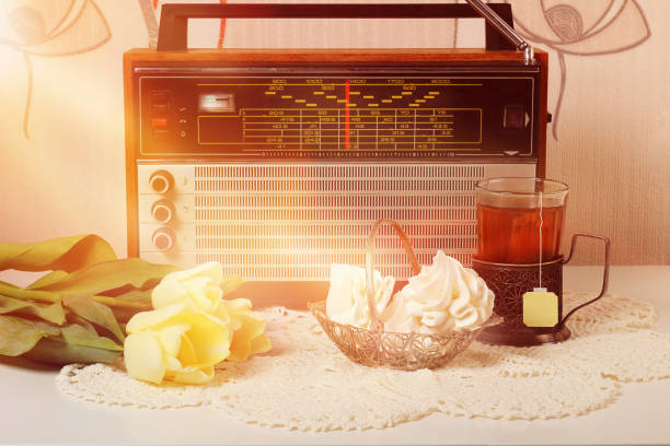 concept du matin, radio vintage, meringues français dans un vase, thé en verre et tulipes jaunes sur une serviette blanche. fond vintage ou rétro, vue latérale, espace de copie. - gods rays audio photos et images de collection