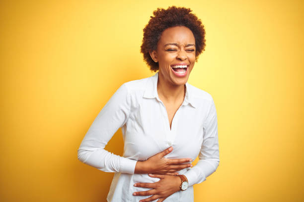 African american business woman over isolated yellow background smiling and laughing hard out loud because funny crazy joke with hands on body. African american business woman over isolated yellow background smiling and laughing hard out loud because funny crazy joke with hands on body. people laughing hard stock pictures, royalty-free photos & images