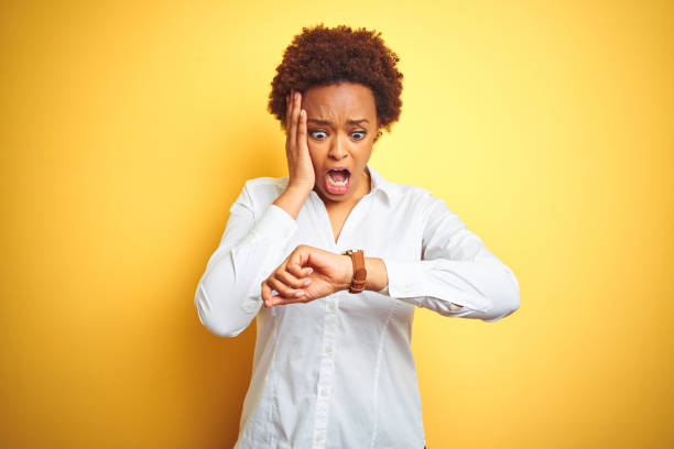 афро-американская бизнес-женщина на изолированном желтом фоне глядя на время часы волновались, боясь опоздать - checking the time women impatient wristwatch стоковые фото и изображения